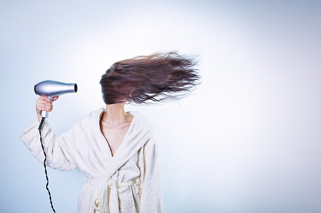 žena fénující si vlasy